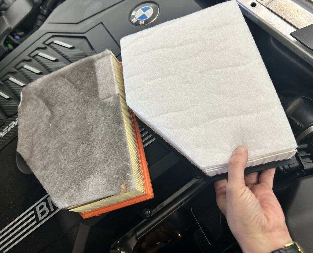 Dirty and clean BMW engine air filters during routine maintenance service at Chimney Rock Car Care in Houston, TX