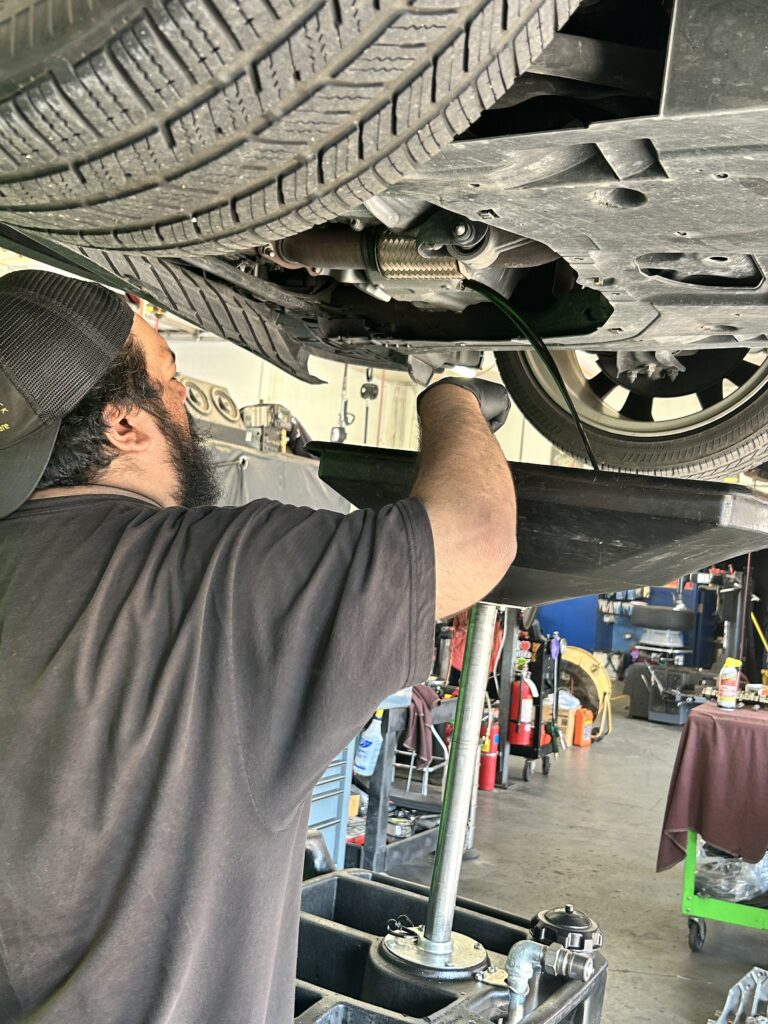 oil change service in Houston mechanic draining engine oil under vehicle