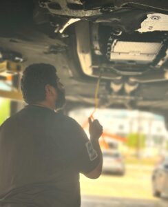 Technician inspecting transmission fluid on BMW in Houston auto repair shop