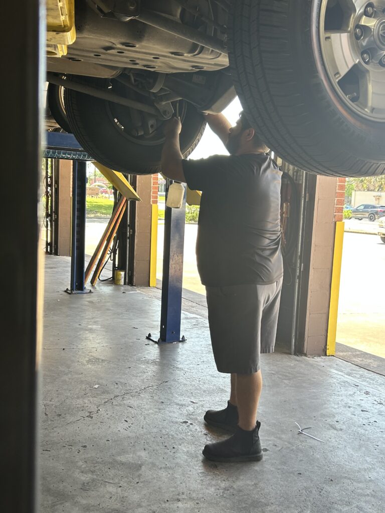 Technician bleeding brake fluid after brake caliper replacement on Toyota 4Runner in Houston