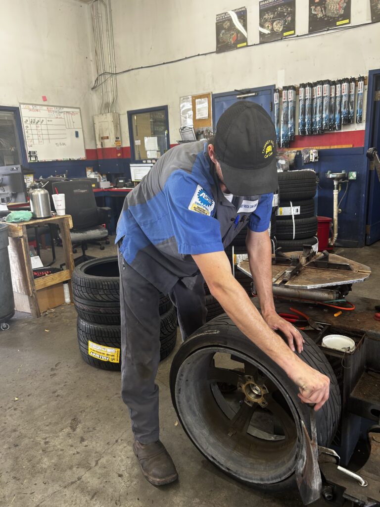 repair or replace your car technician replacing tire during vehicle maintenance at Chimney Rock Car Care