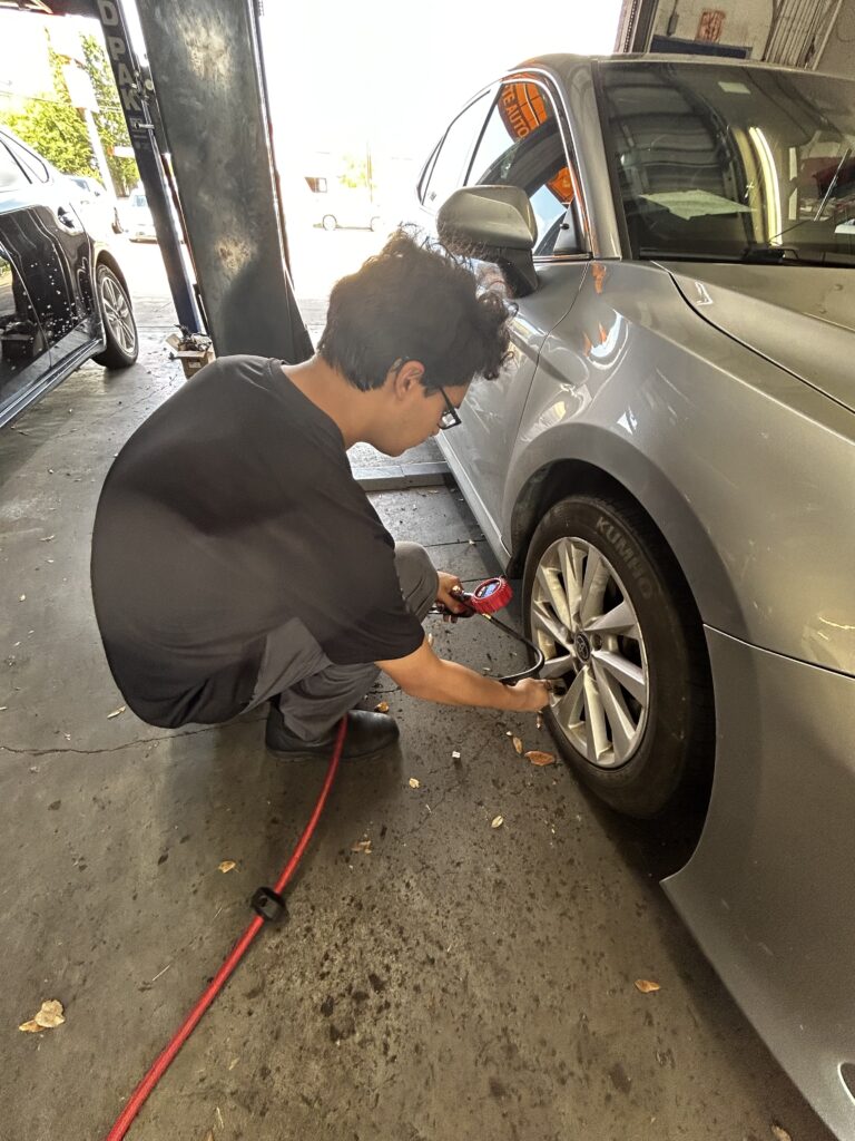 Technician checking tire pressure during a back-to-school vehicle check