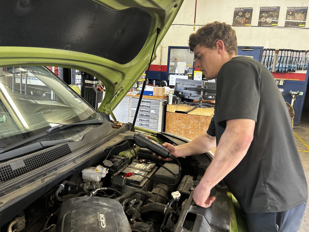 Technician testing a car battery at Chimney Rock Car Care in Houston