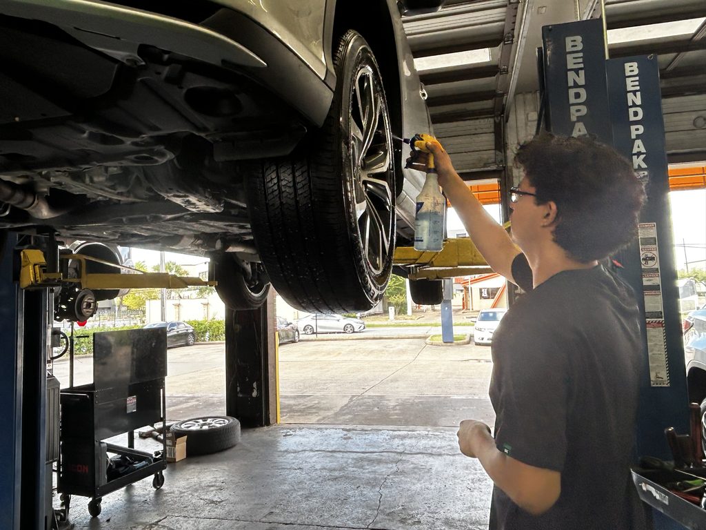 Technician checking a tire during a wet-weather vehicle inspection in Houston