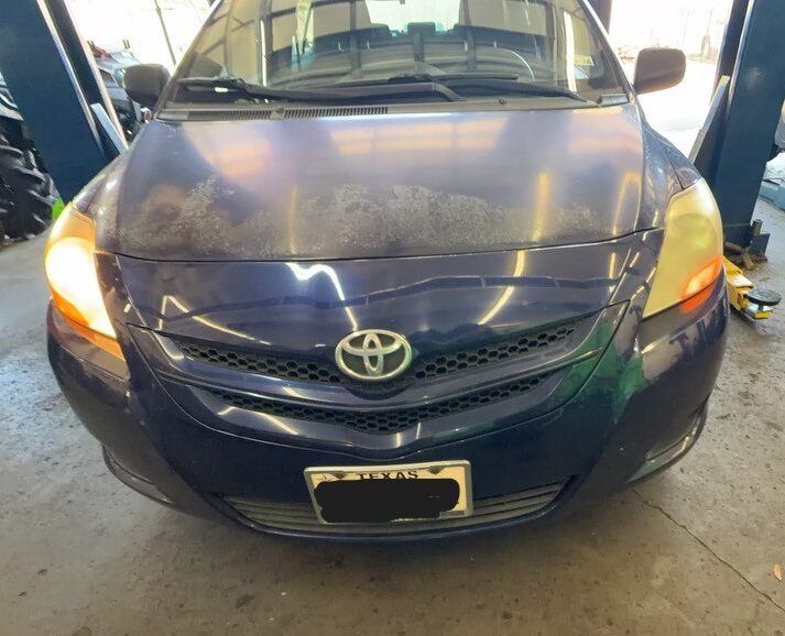 Toyota Yaris in a Chimney Rock Car Care service bay with one headlight illuminated.